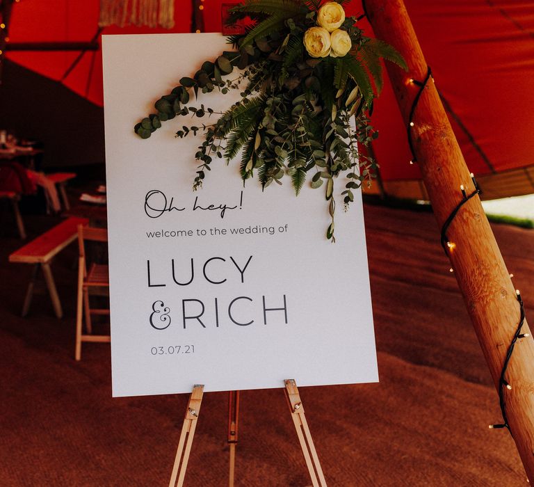 Welcome sign at the front of tipi complete with green floral decor