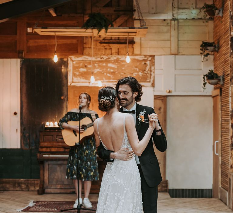 Groom in a black tuxedo dancing with his bride in an appliqué wedding dress on a Persian rug at new Lake District wedding venue , Ghyll Barn