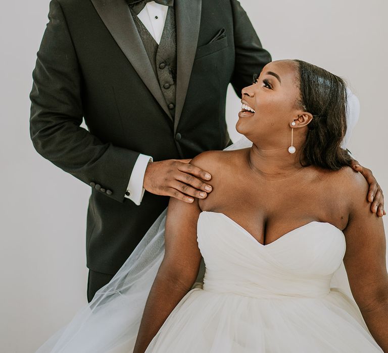 Bride looks up at her groom on wedding day as she wears bridal gown with sweetheart neckline and full skirt