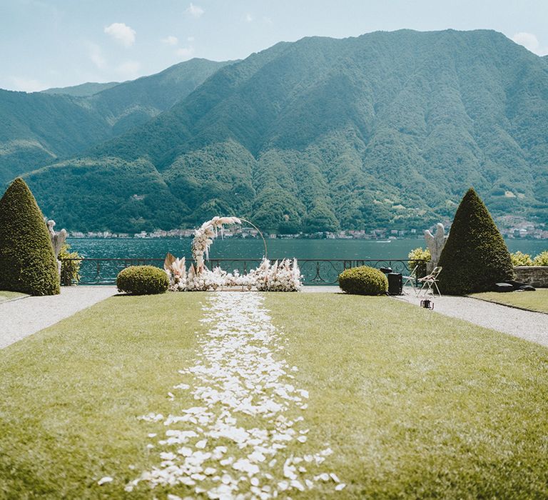 Petal walkway for bride leading to floral installation and a backdrop of Lake Como at the Villa Balbiano