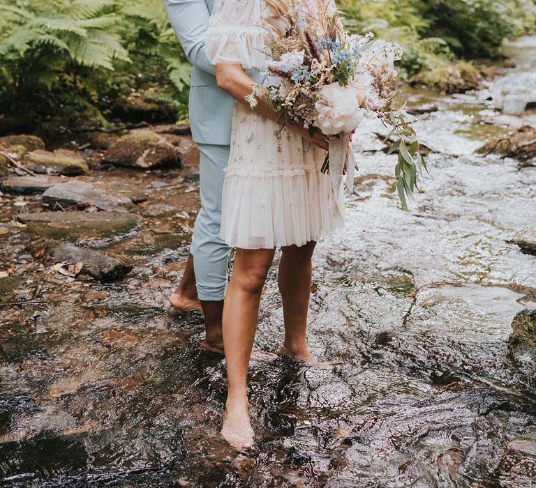 Groom wraps his arms around bride who nears Needle & Thread wedding gown 