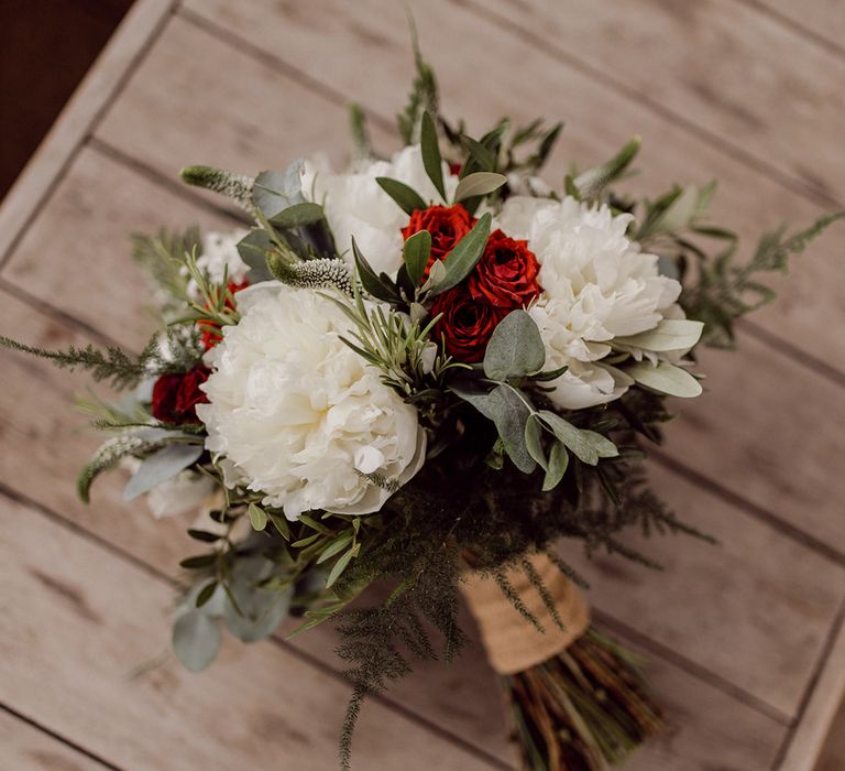 Floral bouquet complete with white flowers and pop of red tied with brown string | Joshua Gooding Photography