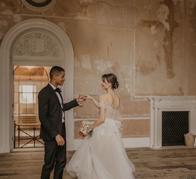 Romantic wedding at Clerkenwell House with groom in a black tuxedo twirling his bride in a tulle wedding dress with lace detail 