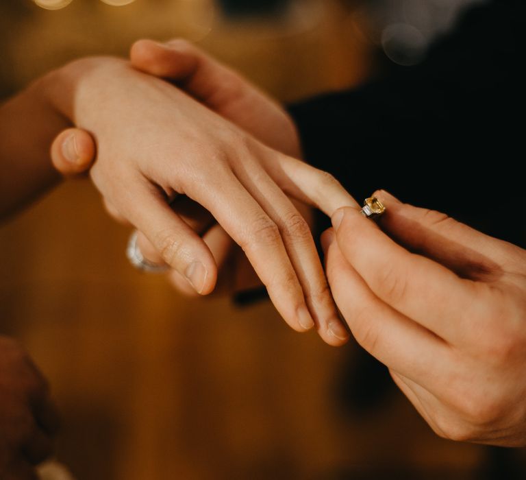 Groom puts vintage wedding ring on brides finger at Wellbeing Farm wedding 