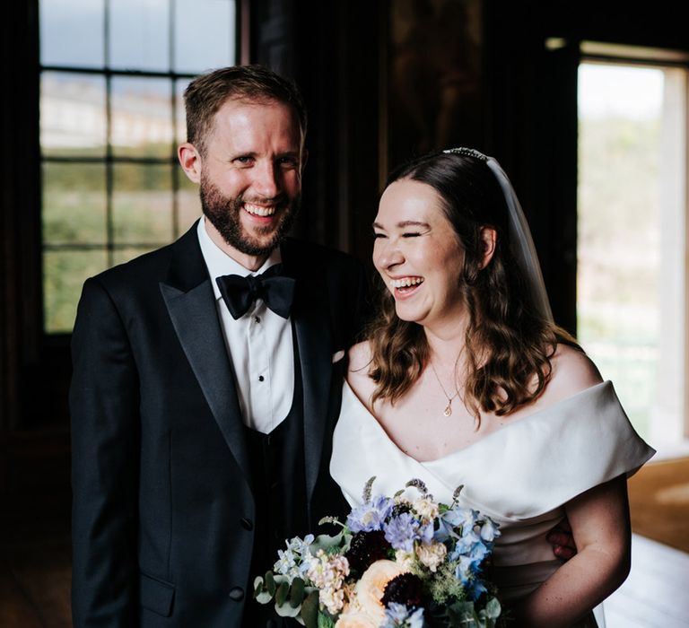 Bride laughs as she wears off the shoulder wedding gown complete with veil