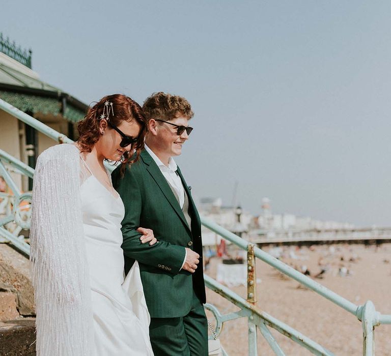 Bride wraps her arms around groom on wedding day by Brighton Pier front