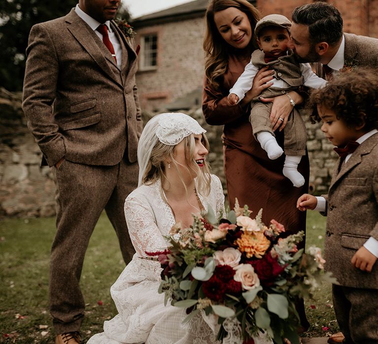 Bride in a lace wedding dress and Juliet Cap veil with her page boys in miniature tweed suits 