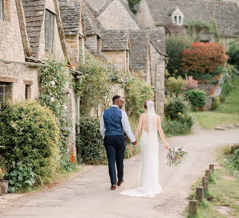 Bride & groom walk hand in hand through the Cotswolds 