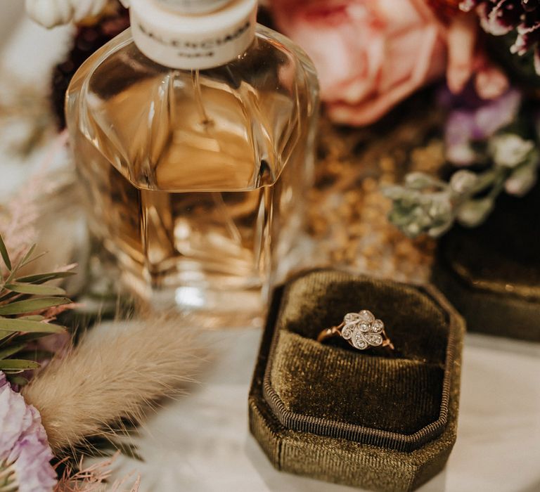 Flower diamond wedding ring in green velvet box next to perfume bottle before wedding