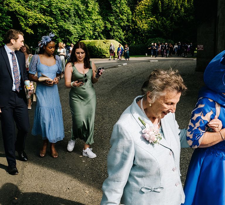 Wedding guests in blues and greens arrive to the wedding at Errol Park