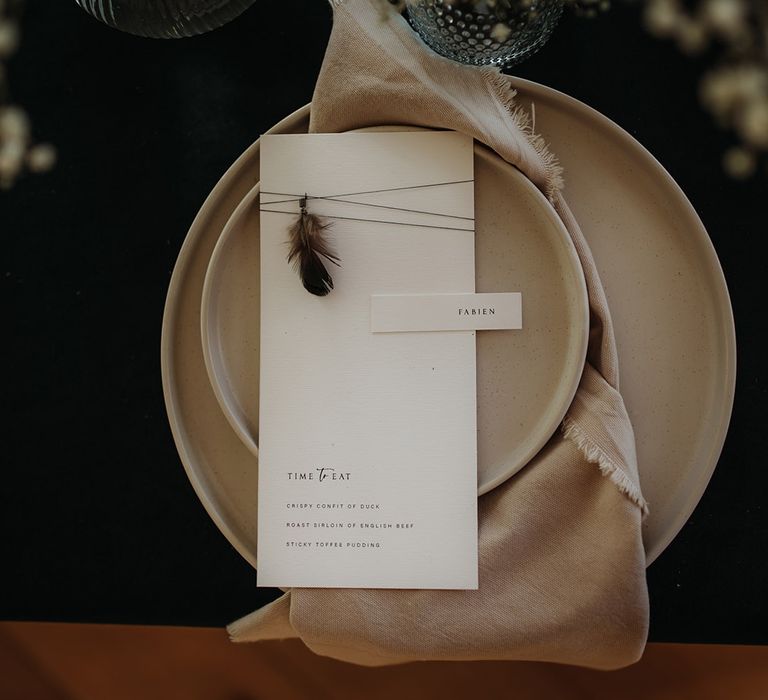 Place setting with beige plates and menu card with feather detail 