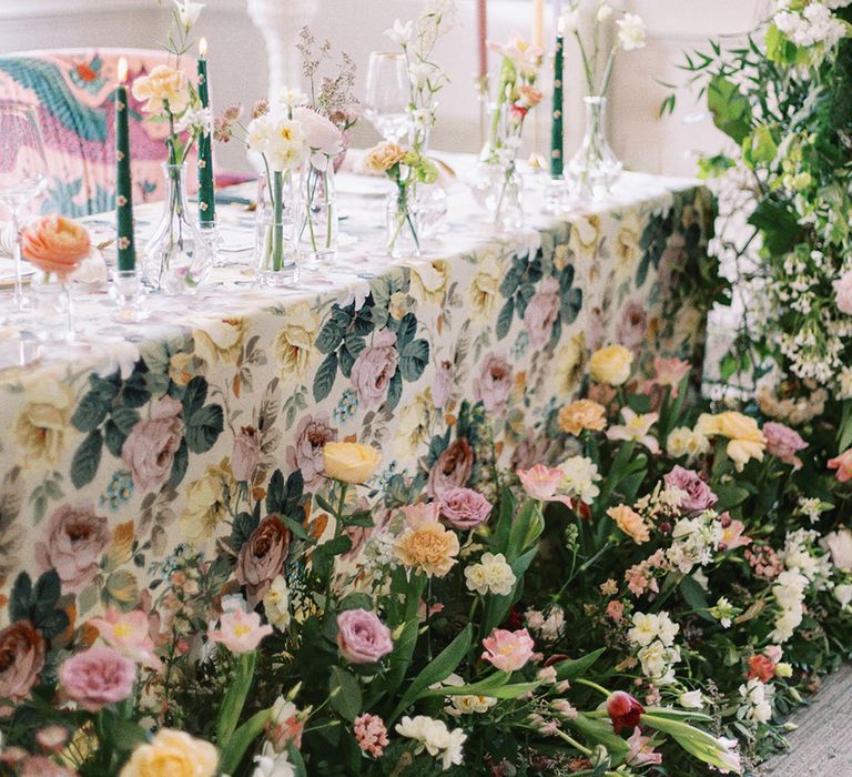 wedding table decor with flower table cloth and flower stems in glass vases 