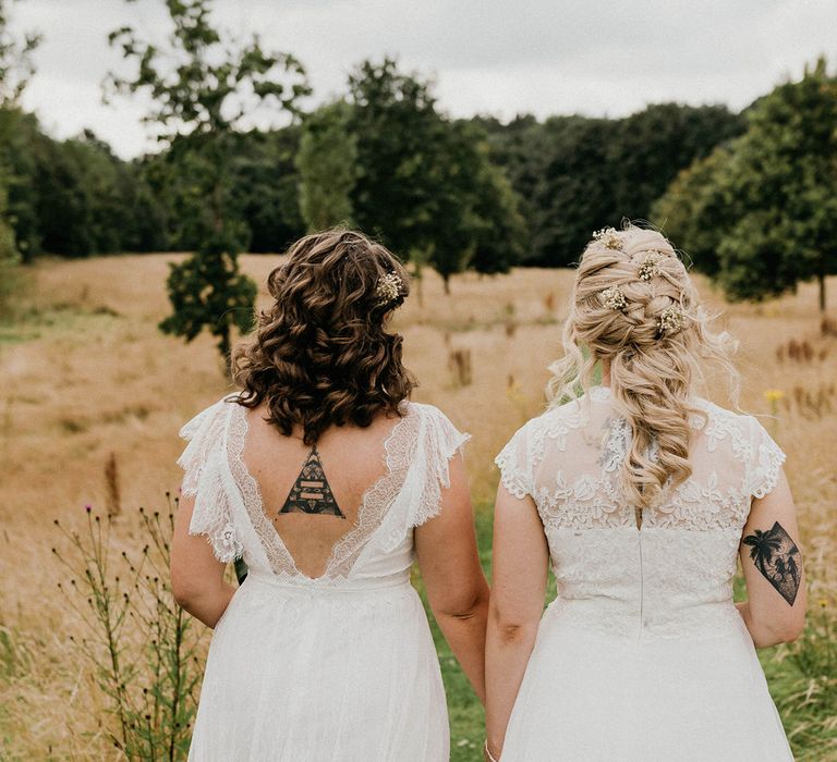 Bride with brunette short curled hair and blond bride with braid hairstyle and gypsophila hair pins walk together