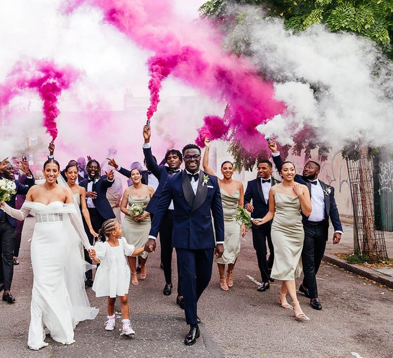 Wedding party walk the streets in celebration of marriage with hot pink smoke bombs