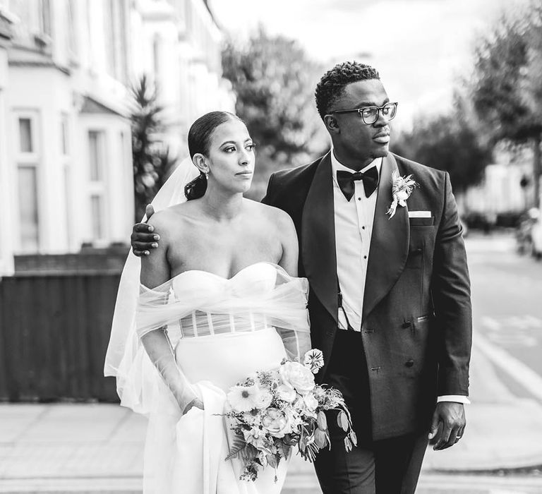 Groom in black and blue tuxedo with bride in off the shoulder wedding dress with corset style top