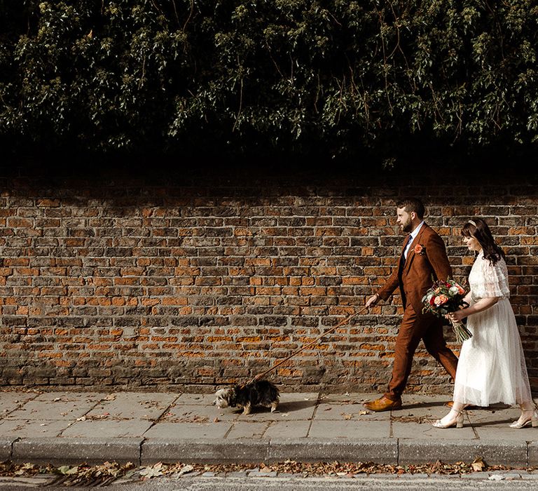 Bride and groom take their dog for a walk with them on their wedding day 