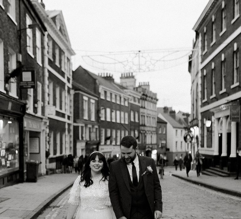 Bride and groom hold hands as they walk around the city of York where they met for the first time