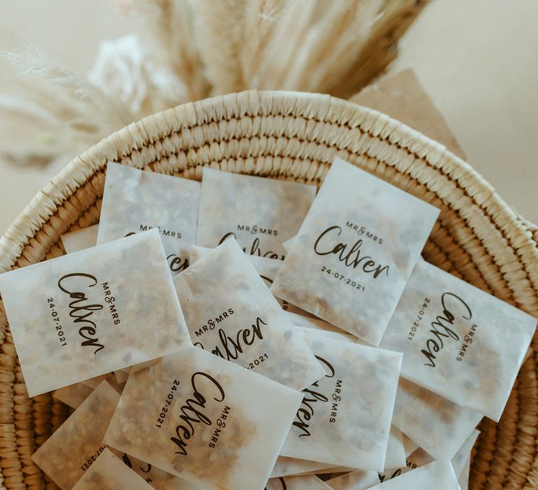 Wicker bowl of confetti in pouches with personalised details including date and name of the couple 