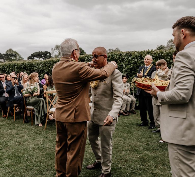 Milni ritual at outdoor multicultural wedding with yellow flower garlands 