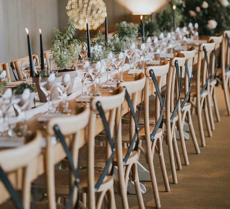 Black taper candles all along the table with greenery