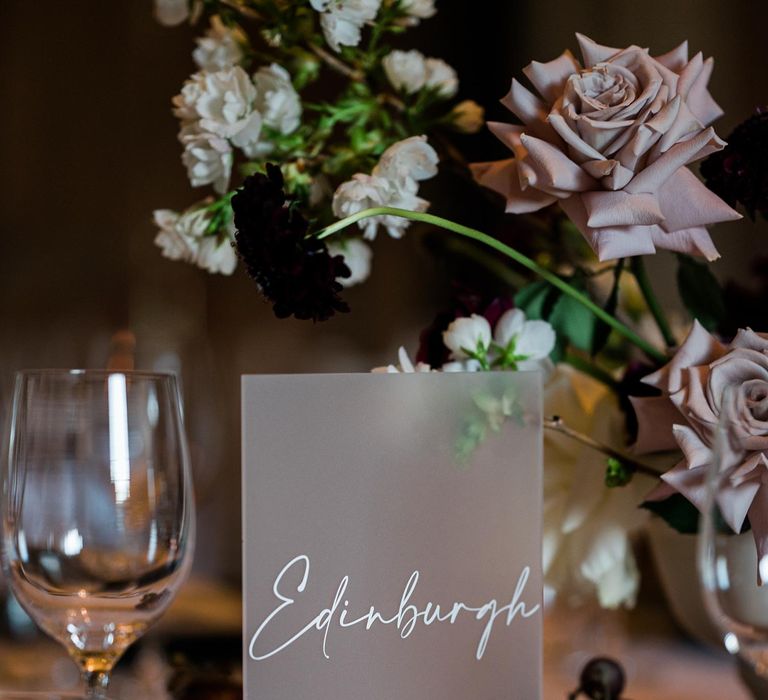 Frosted glass table names complete with white calligraphy writing and bunches of grapes