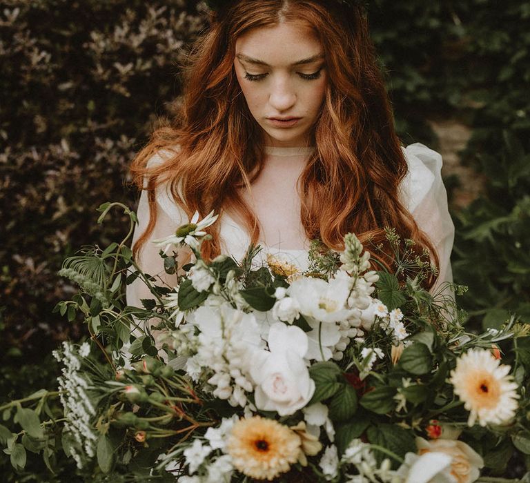 Bride with long wavy red hair and natural wedding makeup wearing a green flower crown holding a giant wedding bouquet 