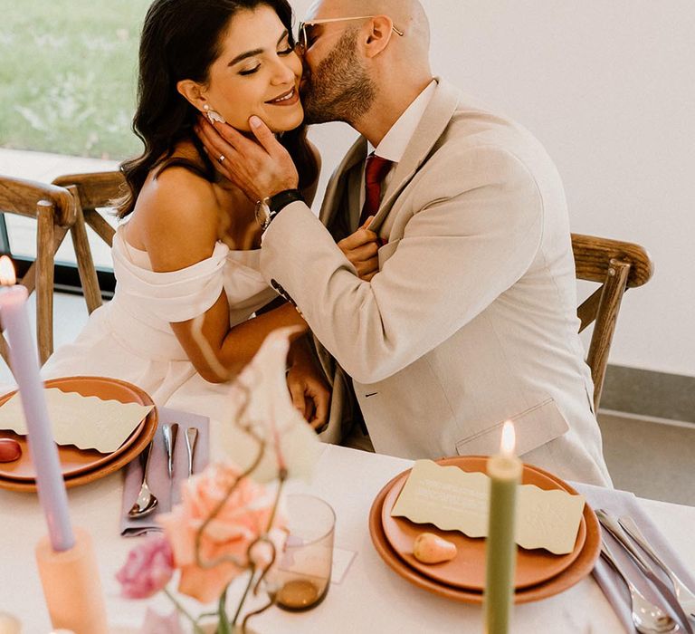 Groom gives the bride a kiss on the cheek on their wedding day 