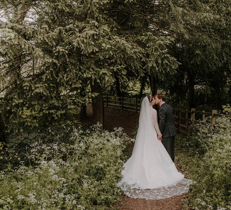 The bride and groom share a kiss in the grounds surrounding their marquee reception 