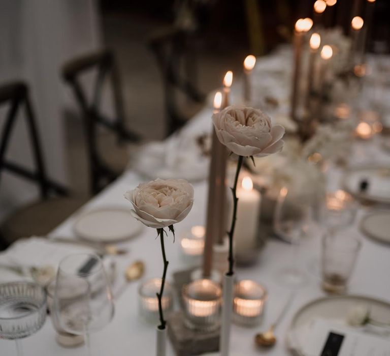 Two light toned roses in thin ceramic vases on neutral minimalistic wedding tablescape