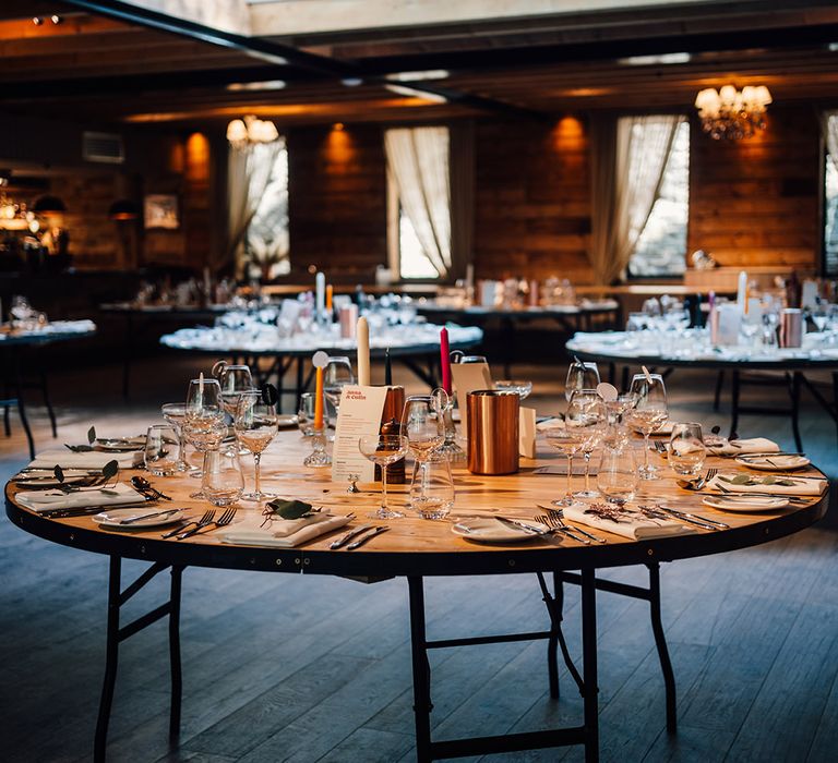 Round wooden tables finished with colourful candles for wedding reception 