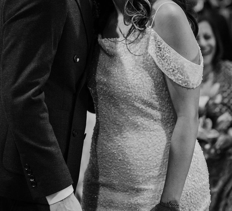 Bride in sequin embellished wedding dress hugs her groom during civil ceremony 