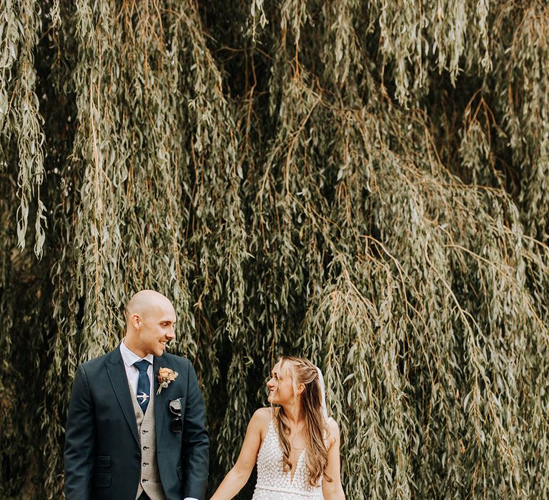 Duddon Mill Farm wedding with the groom in a three piece navy and grey checkered suit with the bride in a patterned wedding dress 