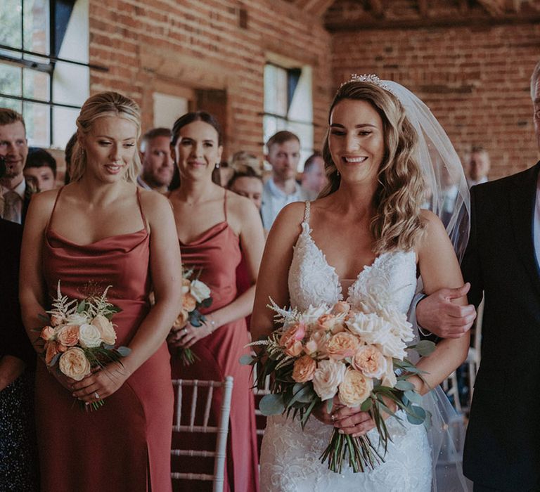 Father of the bride wearing a navy suit jacket with a striped tie walks the bride to the end of the aisle for the rustic Stanlake Park wedding 