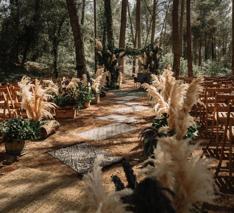 Big and fluffy pampas grass aisle decor with rugs at woodland wedding 