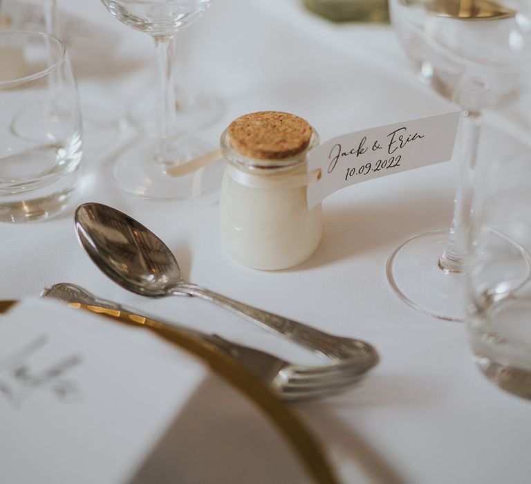 Small glass pot wedding favours with cork lid and personalised label with the date of the wedding and the couple's names 