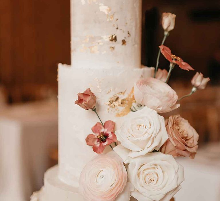 Three tiered buttercream wedding cake with pink dried flower and pearl wedding cake decorations and subtle gold flecks