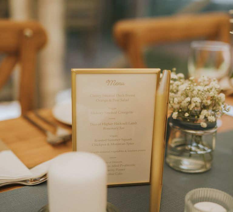 Gold framed wedding menu surrounded by candles at Badgers Holt wedding venue 