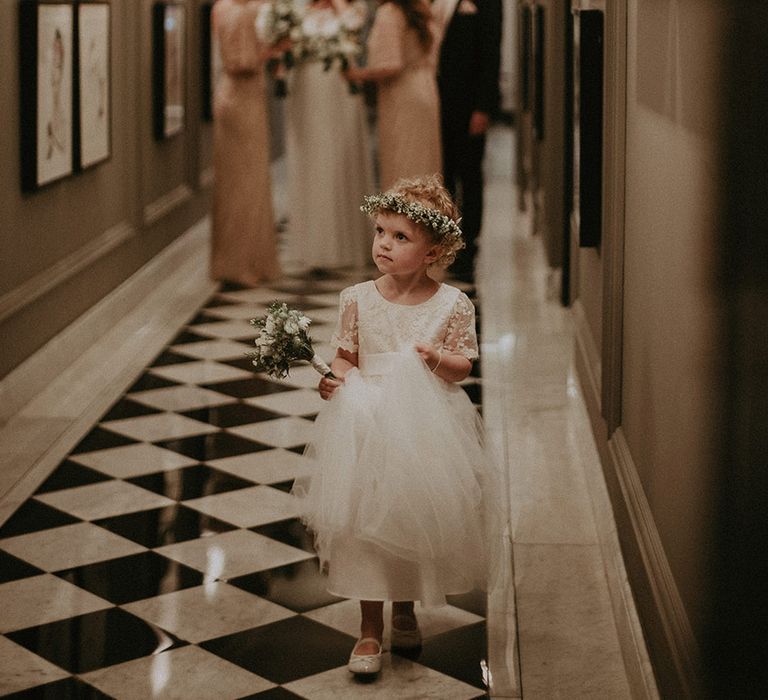 Flower girl wearing a white flower crown and holding white bouquet in a tulle dress for the traditional hotel wedding in London