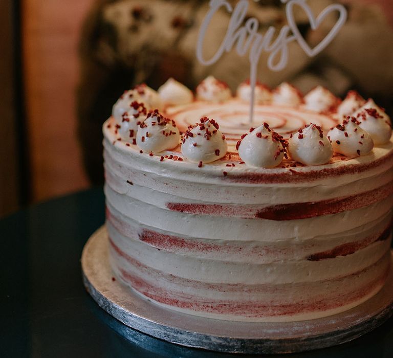 Single tier frosted wedding cake with white cake topper 