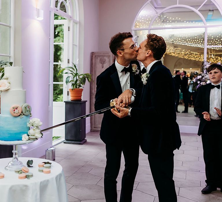 The grooms cut their wedding cake with sabre sword at Deer Park Country House 