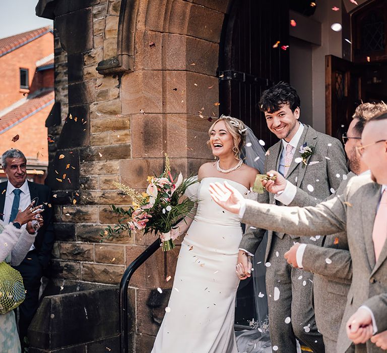 The bride and groom have a confetti exit from their church wedding ceremony 