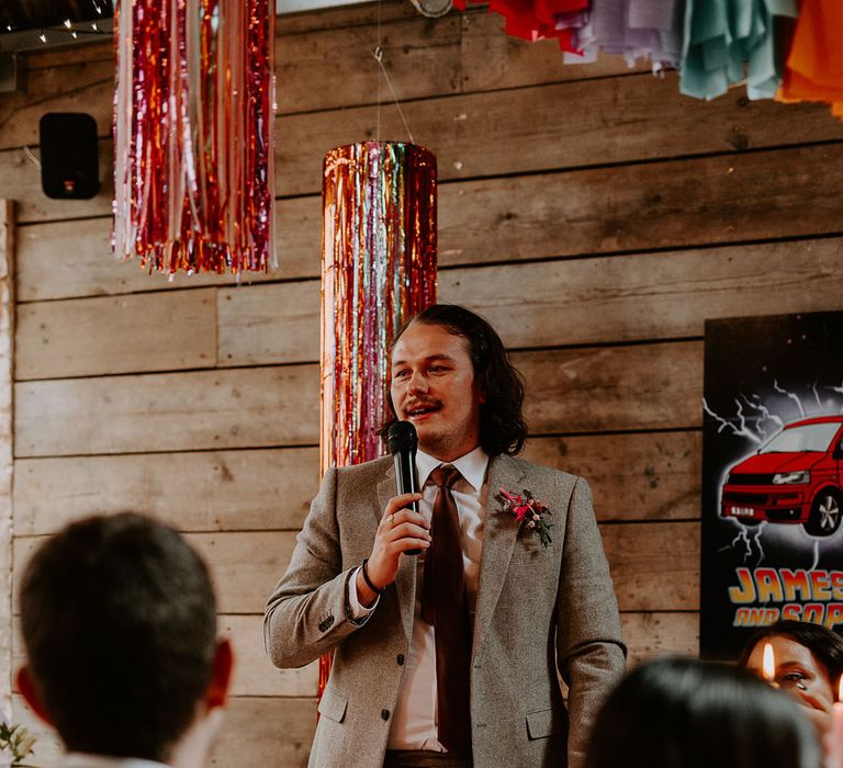 Best man speech at wedding standing next to metallic streamer decorations 