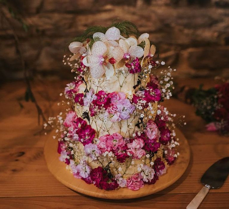 Three tier simple wedding cake decorated with pink flowers and gypsophila 