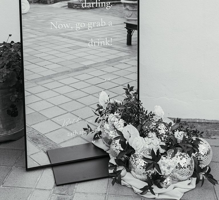 Arched wedding mirror with neutral wedding flowers and disco balls 