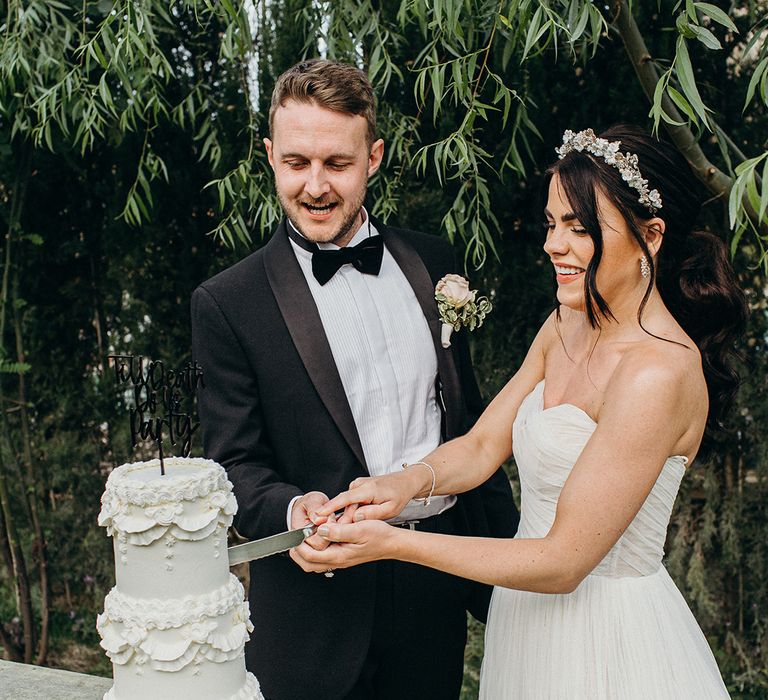 Bride and groom cut their three tier retro wedding cake with custom cake topper 