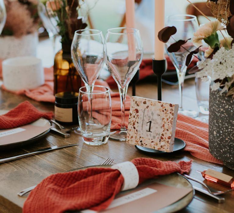 Place setting with burnt orange wedding napkins and terrazzo table numbers 