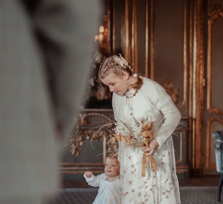 Flower girls walk down the aisle with dried floral bouquet 