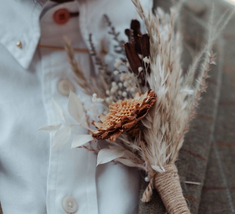 Dried floral buttonhole against Tweed suit