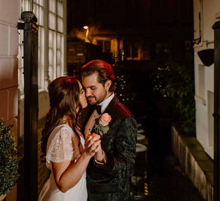 Newly wed bride and groom holding hands for outdoor evening wedding photos