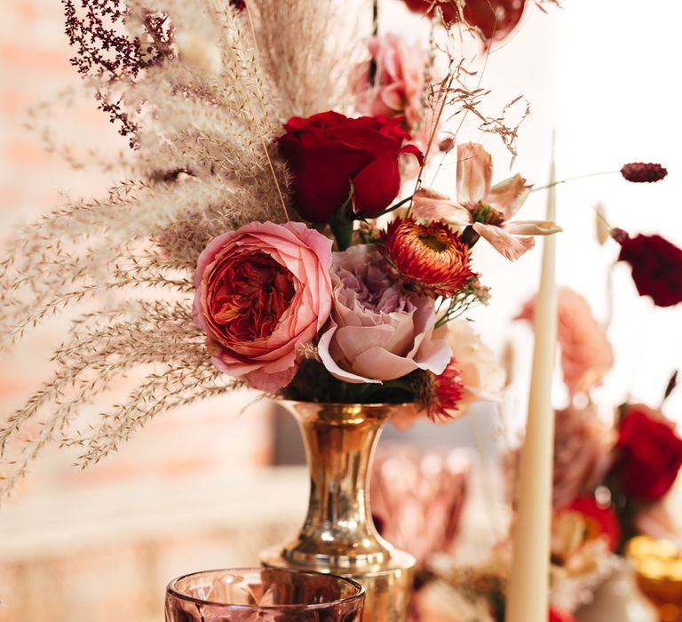 Pink & red floral bouquet in brass vase with pampas grass